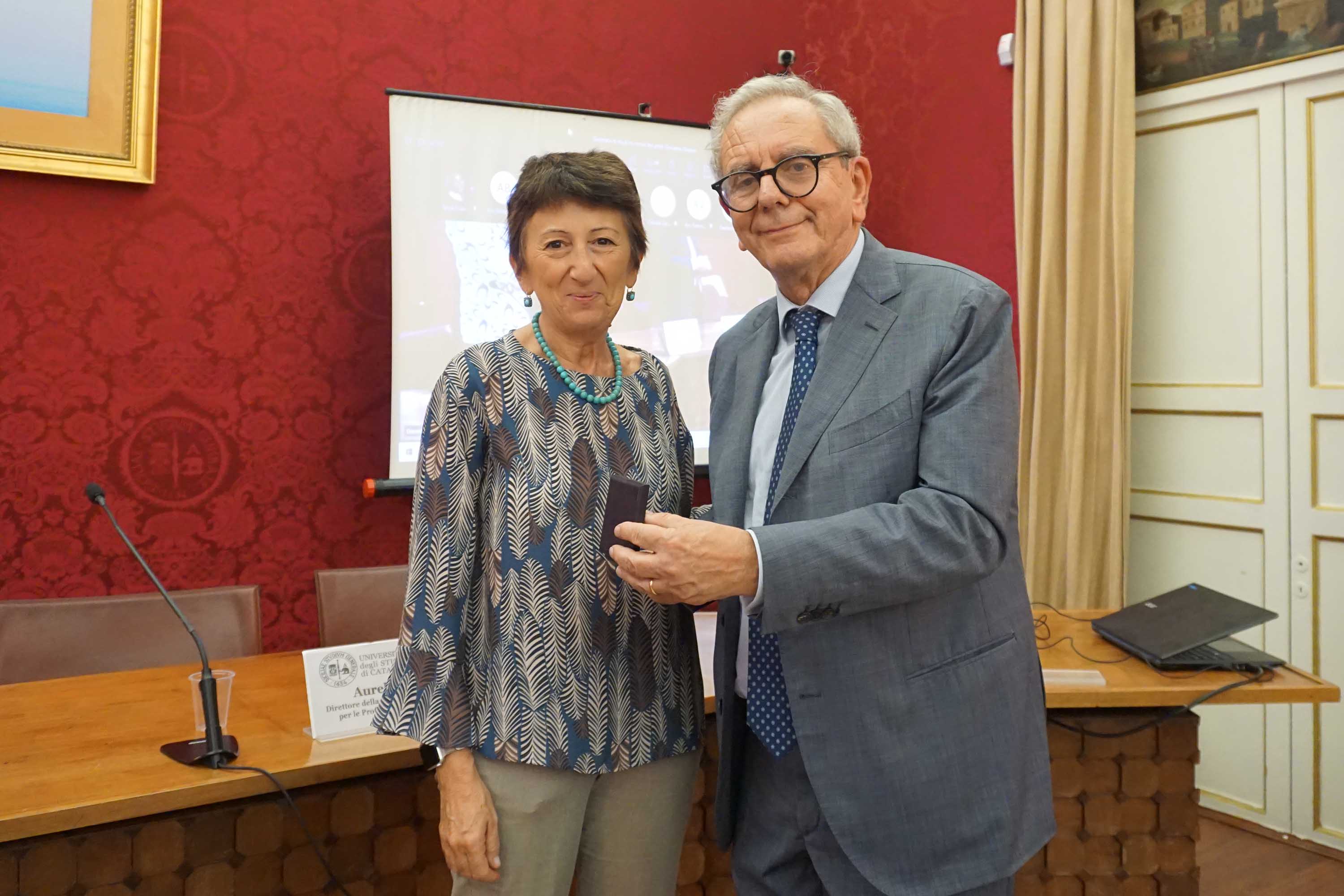 La prorettrice Francesca Longo mentre omaggia il prof. Giovanni Grasso con la "medaglia d'ateneo"
