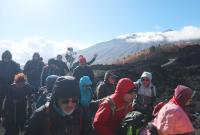 I visitatori mentre attraversano la colata lavica del 2002, sullo sfondo l'Etna